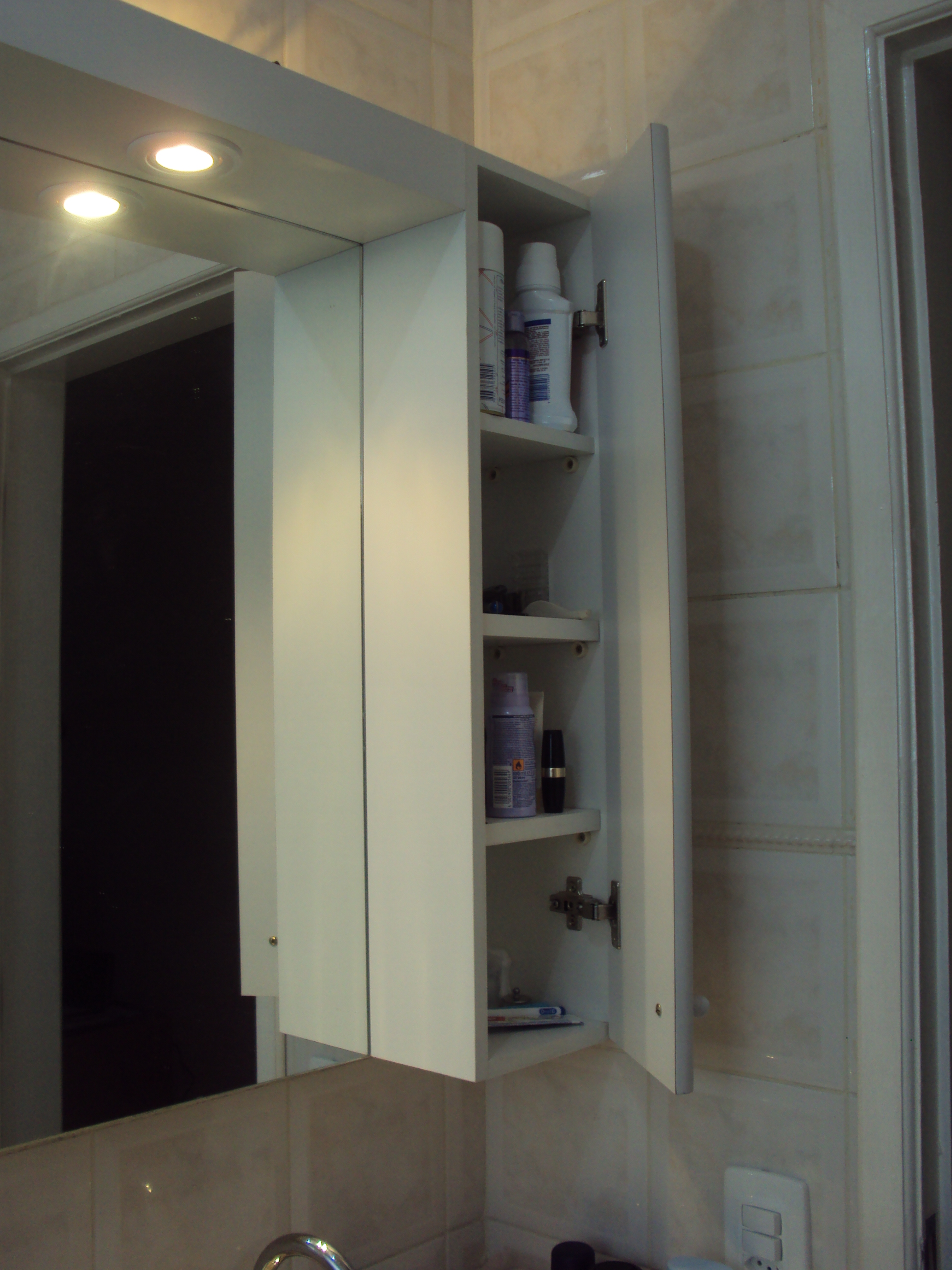 Amarinho para banheiro com espelho, uma portinha com espaço para acomodar seus produtos de higiene, iluminado.