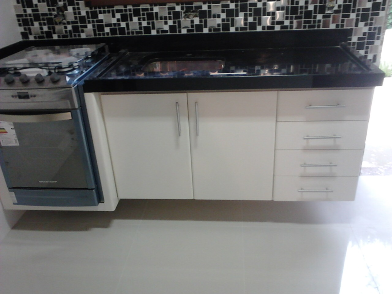 Gabinete para cozinha em fórmica branca acompanhando encaixe para fogão embutido suspenso na parede.